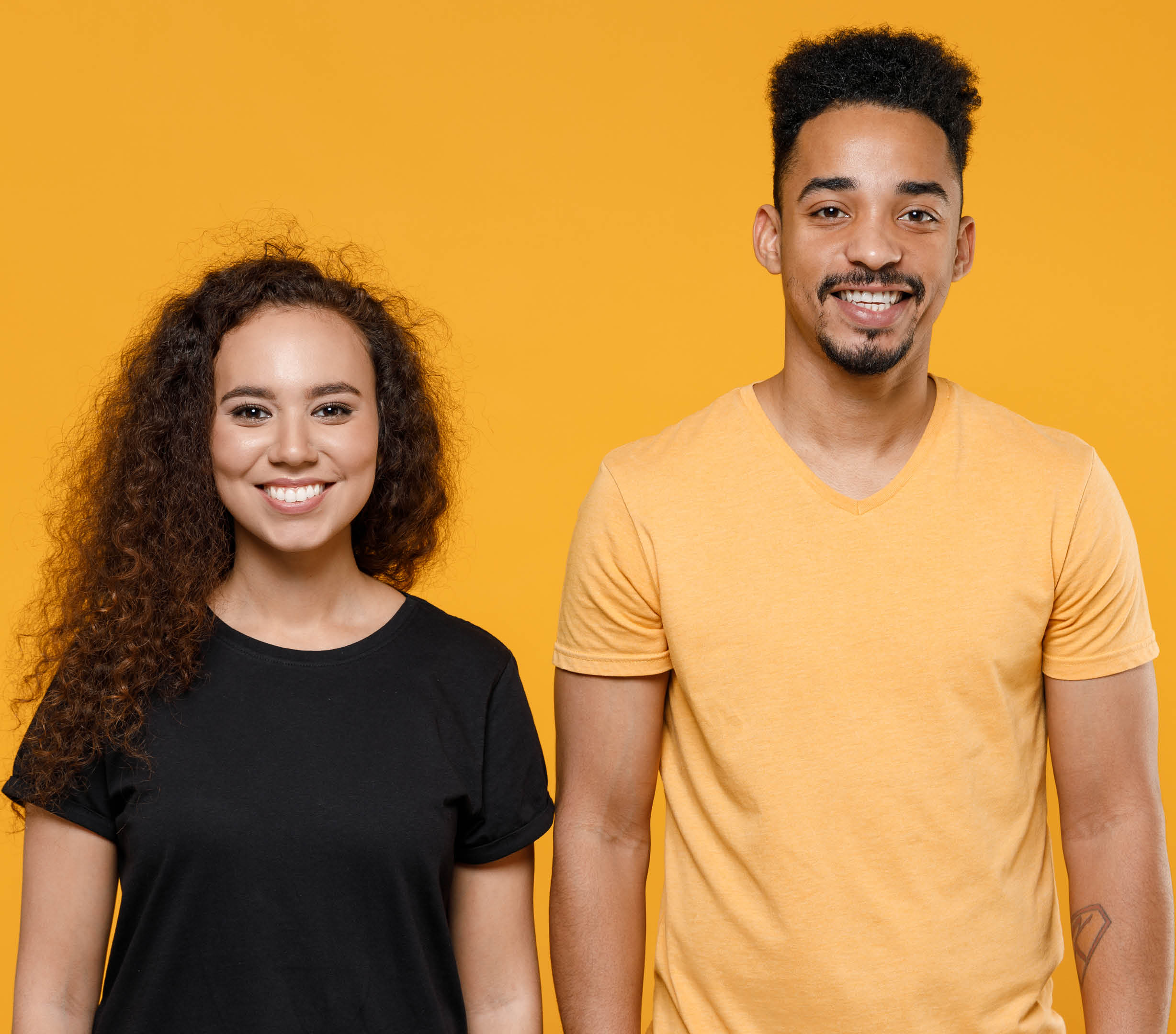 Young couple two american friends family cool happy fun smiling cheerful african man woman 20s together wearing yellow black t-shirt looking camera isolated on orange color background studio portrait
